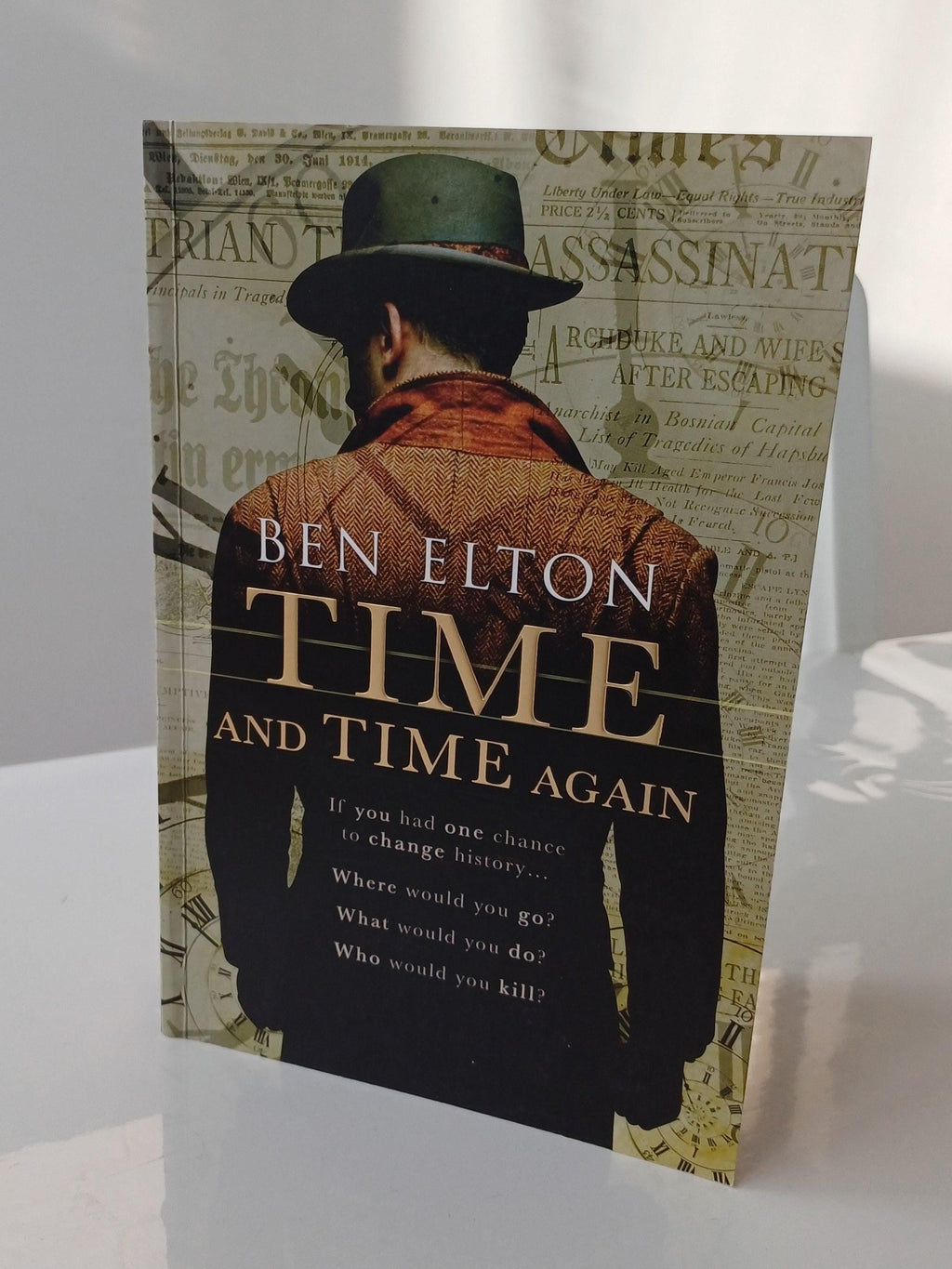 Book cover of 'Time and Time Again' by Ben Elton with a man in a hat and coat on a newspaper background.