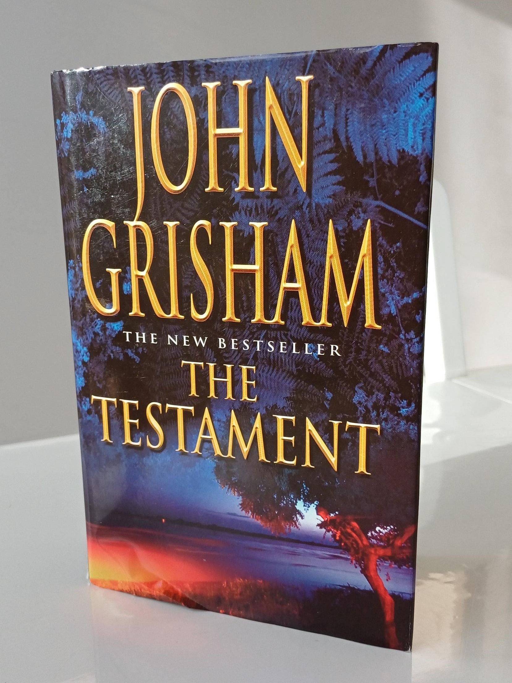 Book cover of 'The Testament' by John Grisham on a white surface
